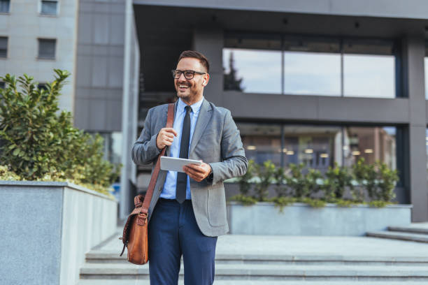 Businessman Standing Outside Modern Office Holding Tablet