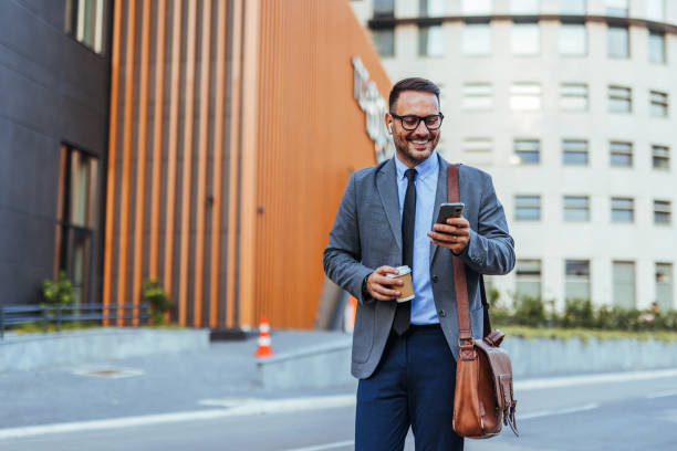istock Confident Businessman Walking and Using Smartphone 2187502504
