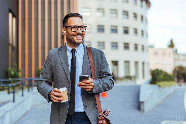 istock Confident Businessman Walking Outdoors with Coffee and Smartphone 2187502506