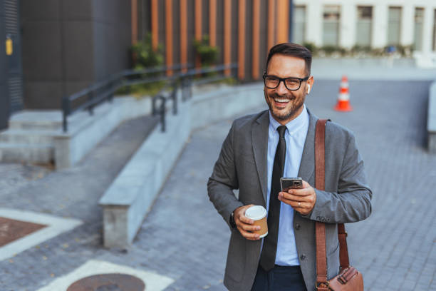 istock Confident Businessman Walking Outdoors With Coffee And Phone 2187502512