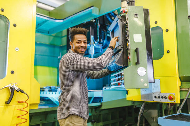 istock Happy Adult Mixed Male Electrical Engineer Looking At The Camera While Setting Up A CNC Machine 2187503692