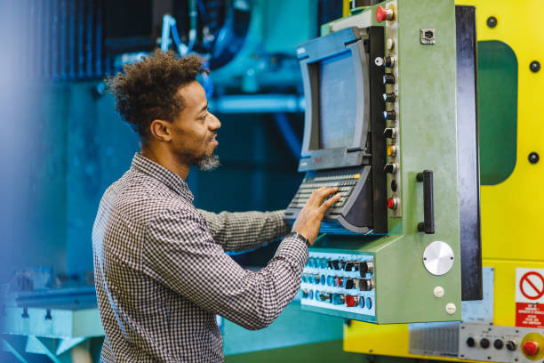 istock Happy Adult Mixed Male Electrical  Engineer Adjusting The Settings On A CNC Machine In A Factory 2187503693