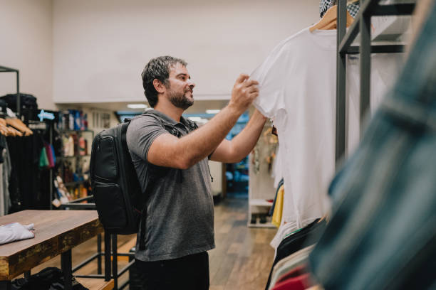 istock Man choosing t-shirt in store 2187505493