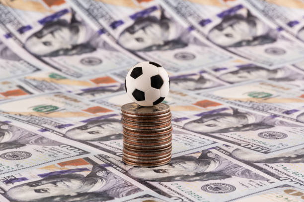 istock Miniature soccer ball with $100 bills in the background 2187531316