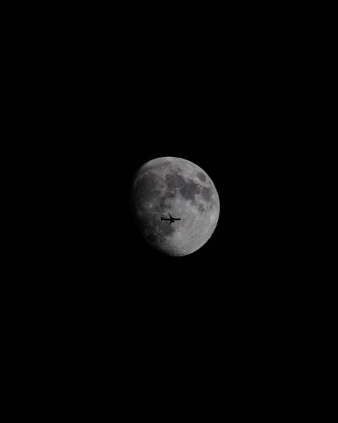 Airplane silhouette crossing the moon in a dark night sky