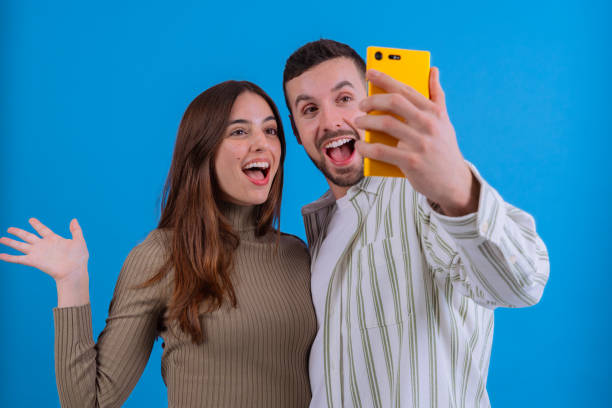 istock Couple taking selfie together with smartphone on blue background 2187532108