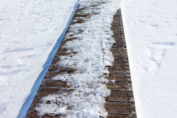 A wooden bridge covered in snow. The snow is piled up on the bridge, making it look like a winter wonderland