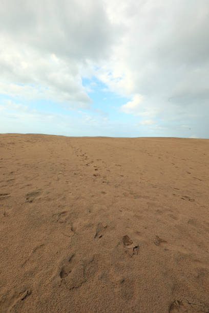Simple background with desert sand dune and sky with a few clouds no people