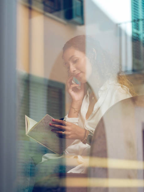 istock Woman with book talking on smartphone in cafe 2187536992