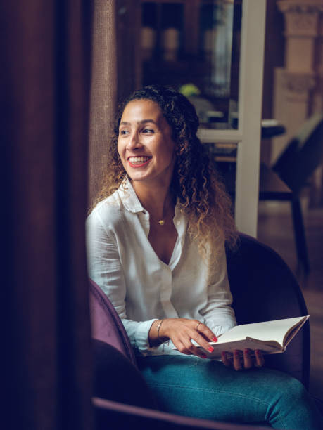 istock Cheerful ethnic woman reading book in cafe 2187537202