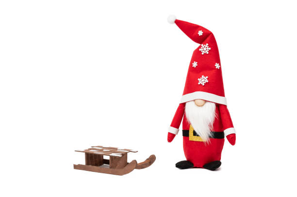 A festive handmade Santa Claus gnome featuring a tall red hat decorated with snowflakes, paired with a small wooden sled. The gnome's long white beard and cheerful design add a whimsical touch to holiday decor.