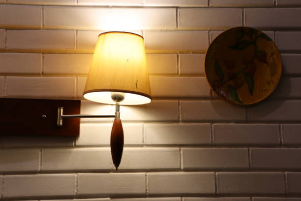 istock Elegant Wall Lamp paired with a Decorative Plate adorning a rustic Brick Wall background 2187539921