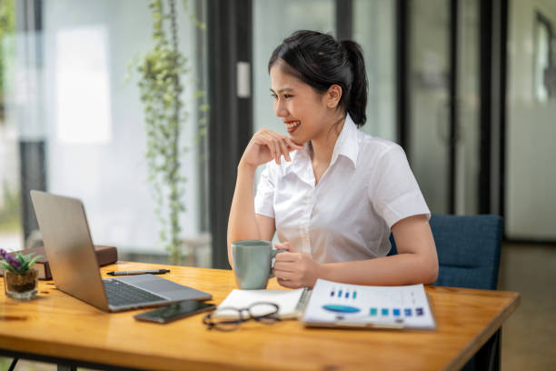 istock Businesswoman enjoying coffee while video chatting on laptop at work 2187541635