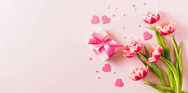 istock Pink tulips and hearts, gift box with ribbon on light pink background 2187543410
