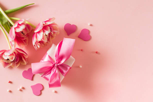 istock Pink tulips and hearts, gift box with ribbon on light pink background 2187543414