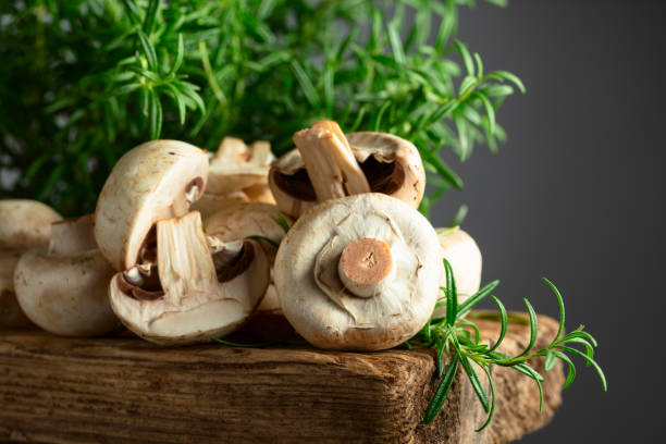 istock White champignons with rosemary on a wooden board. 2187543908