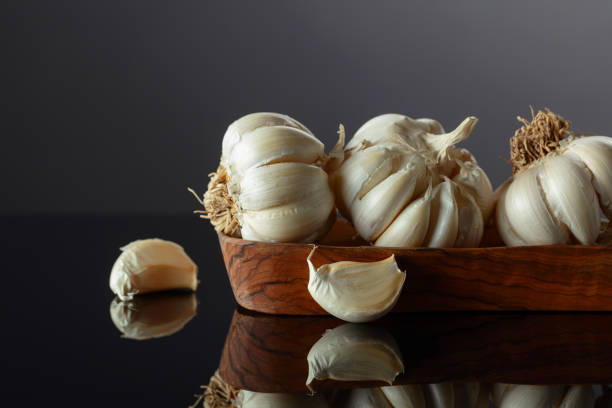 istock Garlic bulbs in wooden dish on a black background. 2187543960