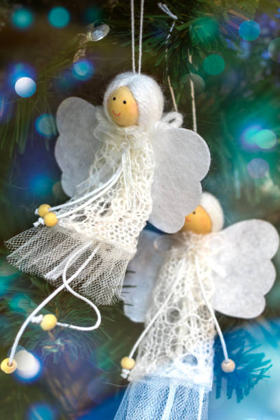 istock Two white hand-made angels decorate Christmas tree 2187546355
