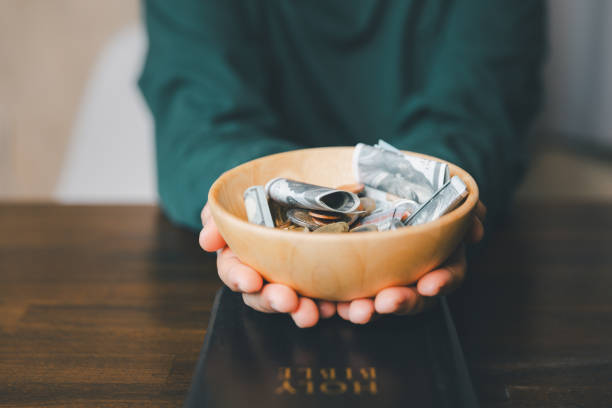 istock He decided to donate portion of his earnings as tithe, giving money and coins as contribution to support financial needs of community. beg, quest, request, desire, need, problem, share, charitable 2187551403