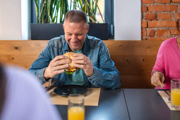 istock Mid-Adult Man Enjoying Burger at Restaurant 2187552527
