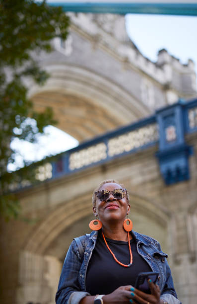 A black woman in holiday in London by the Tower Bridge checking her phone