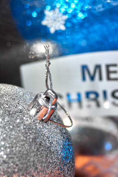 Three silver colored christmas baubles hanging with shiny ropes.