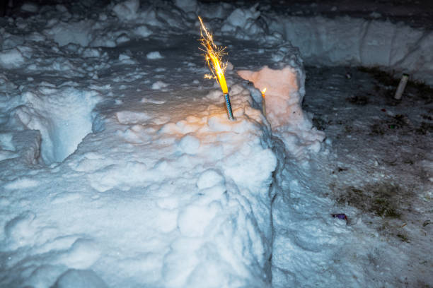 Firework burning brightly in snow during New Year celebration outdoors at night in garden. Sweden.