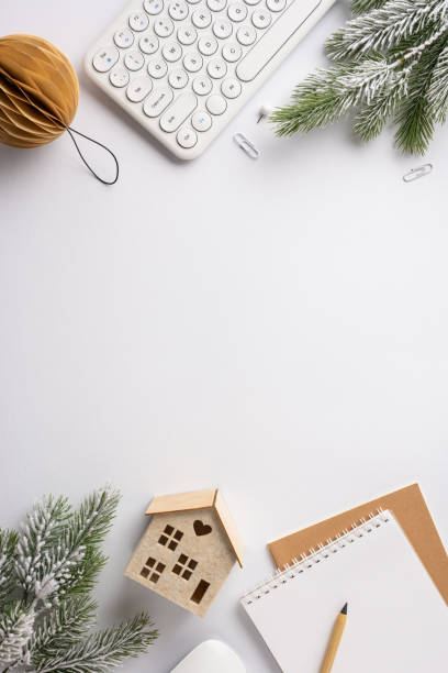 istock A top vertical view of a winter-themed workspace with a keyboard, pine branches, notebook, and decorative items, creating a warm holiday atmosphere 2187575618