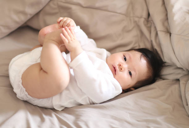 Baby lying on bed and holding legs