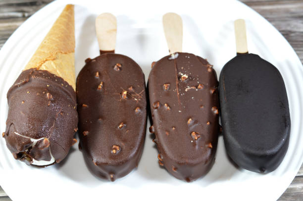 Assorted Ice creams, vanilla cone coated with chocolate layer and nuts in a crispy wafer cone, chocolate and vanilla ice cream stick coated with chocolate layer with nuts, summertime and holidays