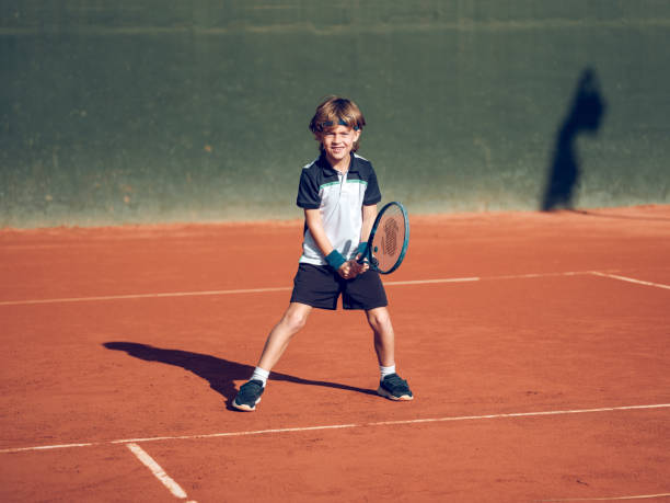 istock Happy child smiling while practicing tennis on clay court 2187584039