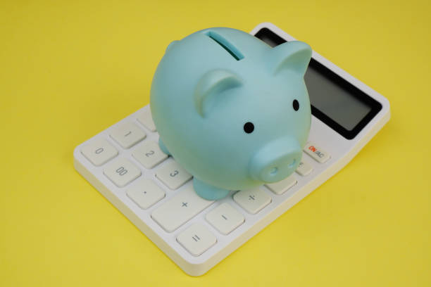 istock Blue piggy bank on white calculator on yellow background. 2187590055