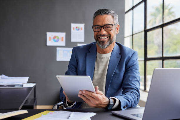 istock Smiling indian businessman working on tablet and smile 2187591989