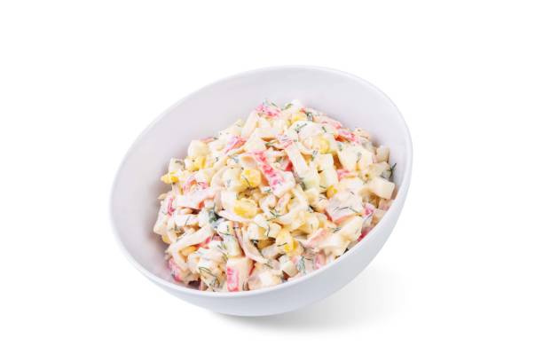Imitation crab meat corn cucumber salad in a bowl on a white isolated background