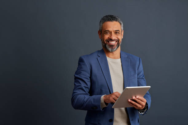 Happy indian mature man holding digital tablet