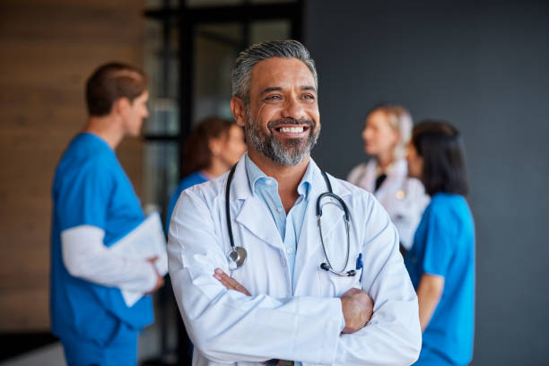 Smiling middle aged indian doctor thinking and looking away