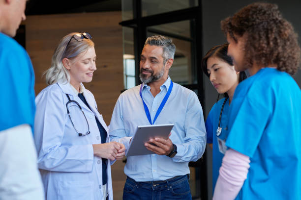 Multiethnic healthcare team meeting pharmaceutical representative Medical mixed race team consulting with pharmaceutical representative at hospital hall. Healthcare hospital staff reviewing new pharmaceutical information. Doctors and nurses discussing healthcare advancements with businessman. medical occupation stock pictures, royalty-free photos & images