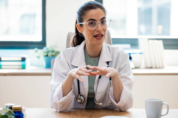 istock Attractive female doctor smiling looking at camera while working with laptop in the consultation. 2187607348