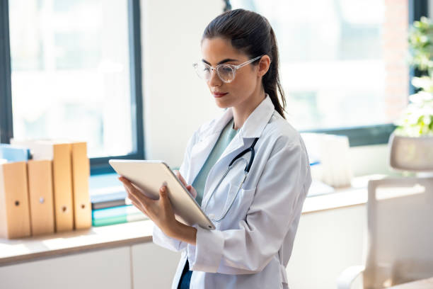 istock Female doctor using her digital tablet while standing in the consultation 2187608161