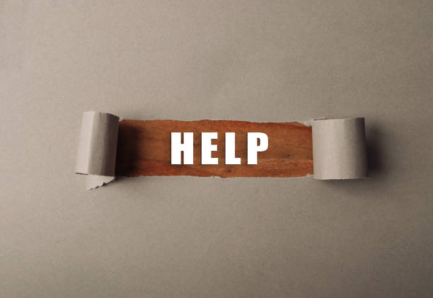 Torn piece of paper with the word HELP written on it. The paper is brown and has a tear in it