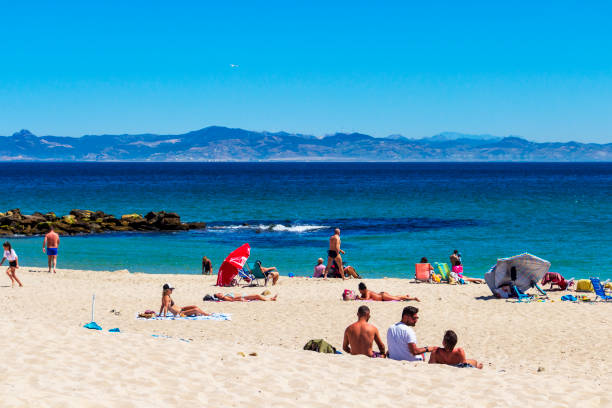 Tarifa, Spain - May 27, 2019: Sunbathing tourists at Playa Chica or Chica beach in Tarifa, Province of Cadiz, Andalusia Spain