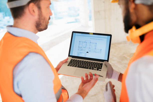 istock Engineer and architect in conversation over building plans on laptop at site 2187612003