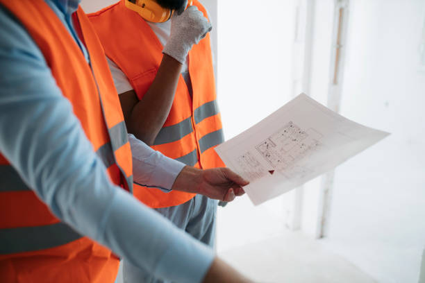 istock Close-up of architect discussing building plan with construction worker working on the site 2187612194
