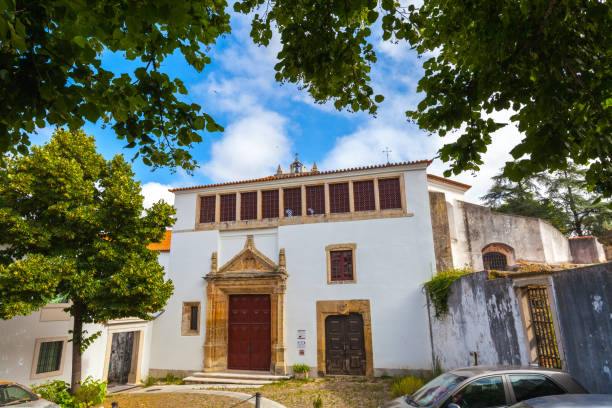 istock A historic building with a whitewashed facade and a prominent stone doorway, framed by lush green trees against a clear blue sky 2187612924