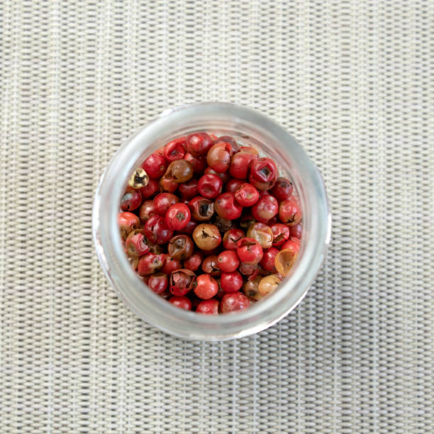istock Red or pink peppercorns on wooden spoon on grey textured cutting board background 2187613269