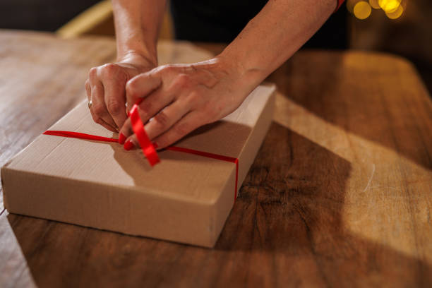 istock Hands tying red ribbon on a gift box on wooden table 2187614315