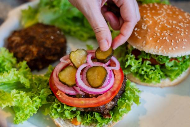 istock Close up view on preparing cheeseburger with vegetables and meat 2187614567