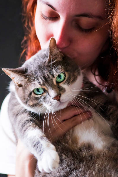 istock Young woman with her eyes closed holding a cat. 2187617134