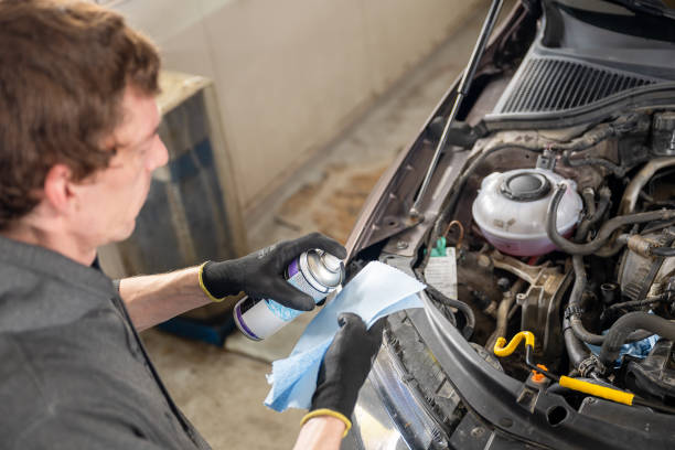 istock Mechanic cleaning car engine using spray and cloth in workshop. 2187617560