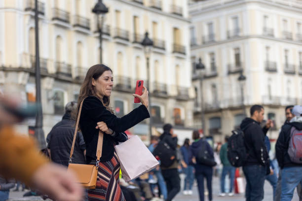 Tourist taking photos at the famous Puerta del Sol in Madrid, Spain Tourist taking photos at the famous Puerta del Sol in Madrid, Spain. The charms of Puerta del Sol make it a very attractive place to take photos: statues, buildings, fountain,... selfie madrid photos stock pictures, royalty-free photos & images